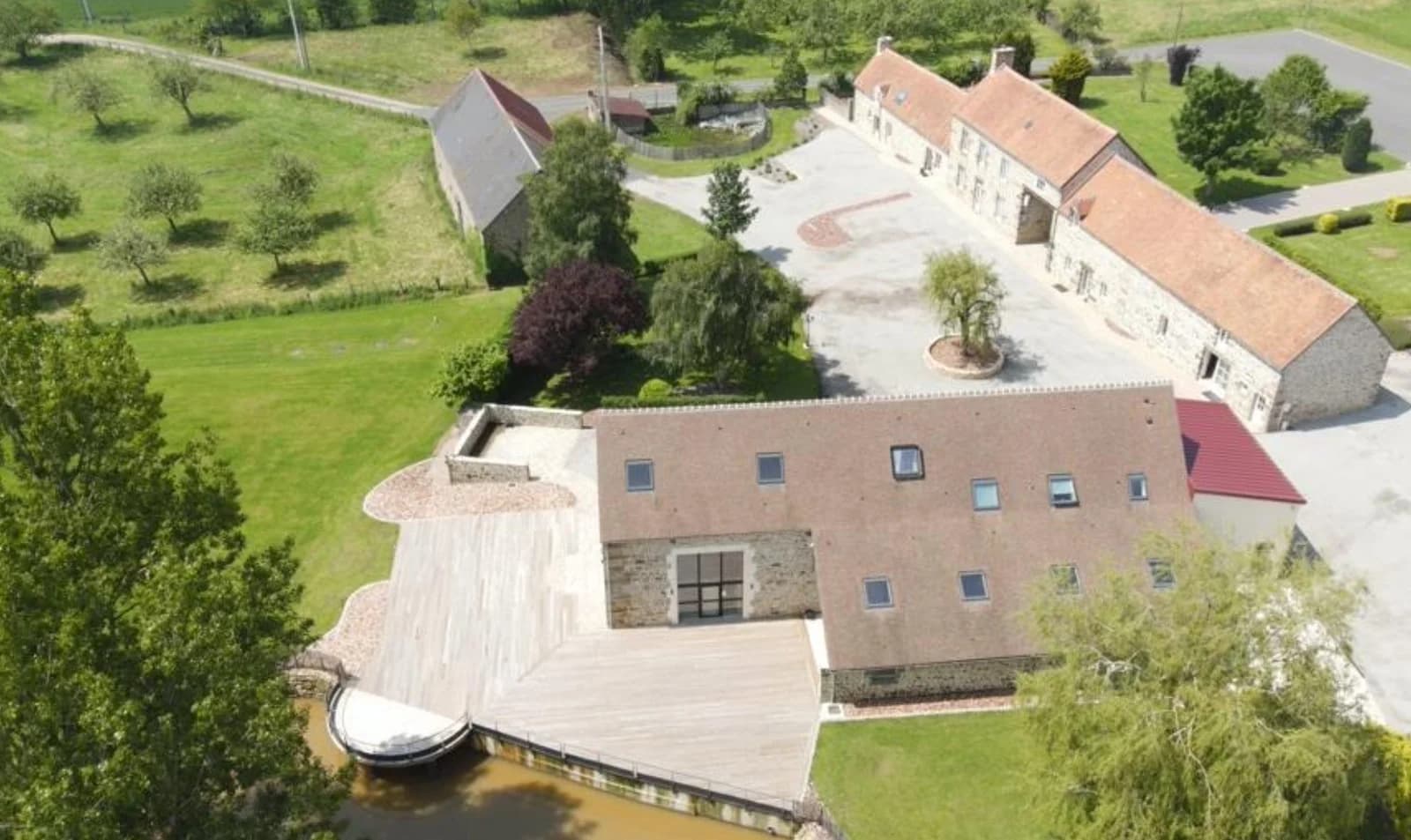 Vue aérienne d’un domaine en pierre, entouré de verdure, au bord de l’eau